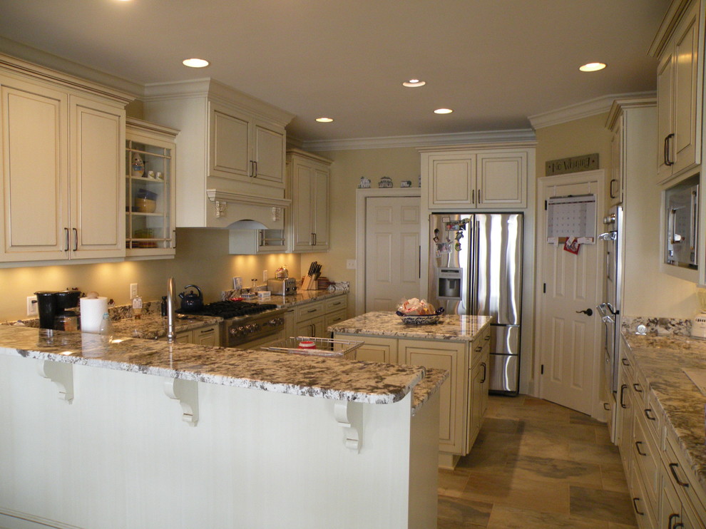 Example of a large classic u-shaped ceramic tile and brown floor enclosed kitchen design in Atlanta with an undermount sink, raised-panel cabinets, white cabinets, granite countertops, beige backsplash, stainless steel appliances and an island