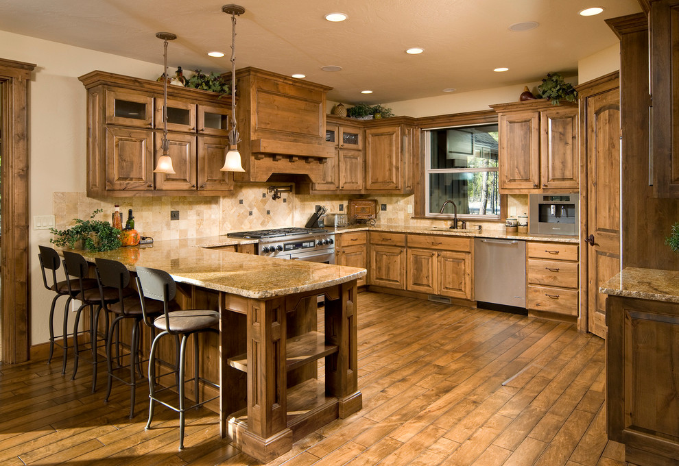Photo of a large rustic u-shaped kitchen/diner in Other with a submerged sink, raised-panel cabinets, medium wood cabinets, granite worktops, stone tiled splashback, stainless steel appliances, medium hardwood flooring and a breakfast bar.