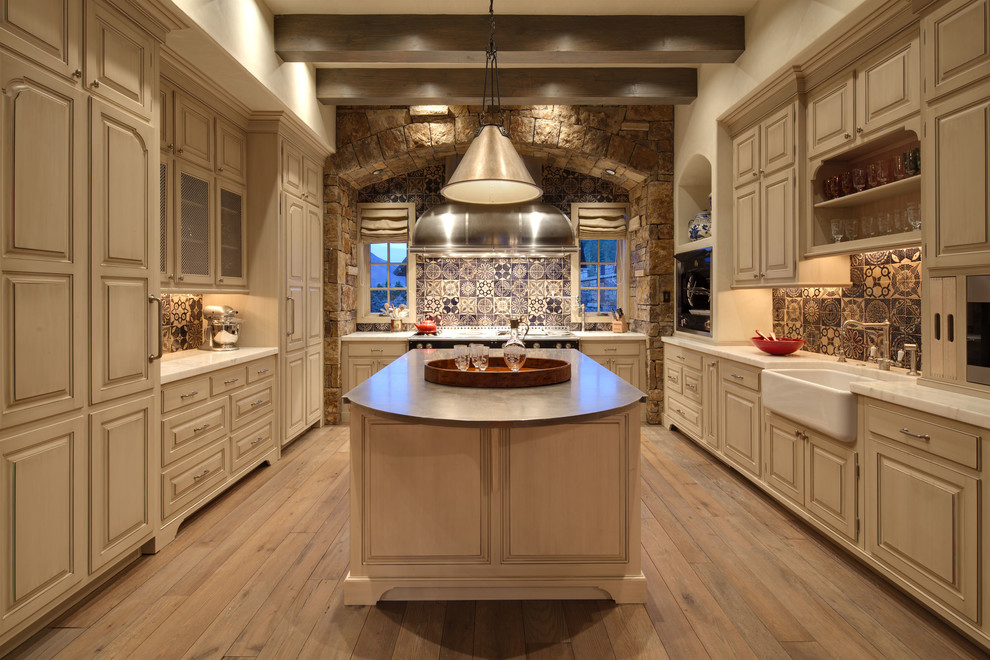 Traditional u-shaped kitchen in Denver with raised-panel cabinets, a belfast sink, beige cabinets and blue splashback.