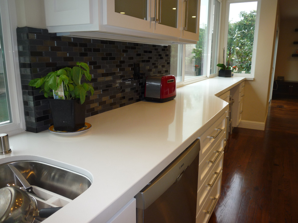 Large classic u-shaped kitchen/diner in San Francisco with a built-in sink, shaker cabinets, white cabinets, granite worktops, multi-coloured splashback, glass tiled splashback, stainless steel appliances, medium hardwood flooring and an island.