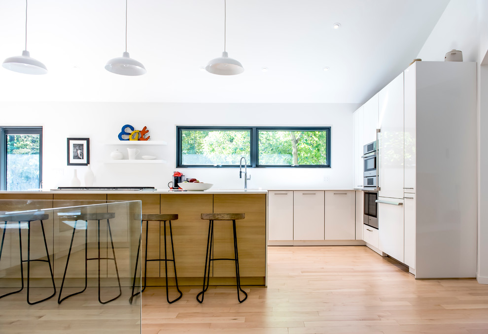 Immagine di una cucina contemporanea di medie dimensioni con ante lisce, ante bianche, top in quarzo composito, parquet chiaro e elettrodomestici da incasso