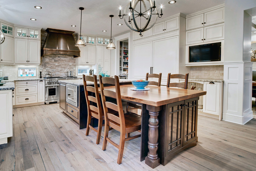 Foto på ett mellanstort funkis kök, med en rustik diskho, granitbänkskiva, beige stänkskydd, rostfria vitvaror, ljust trägolv, en köksö och vita skåp
