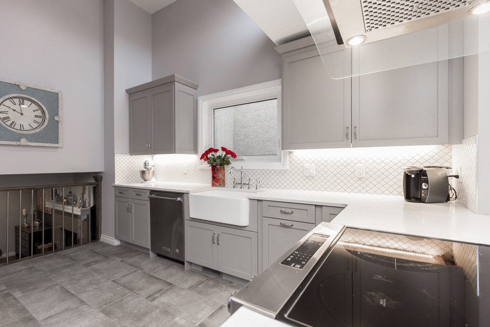 Klassische Wohnküche mit Landhausspüle, Schrankfronten im Shaker-Stil, grauen Schränken, Quarzwerkstein-Arbeitsplatte, Küchenrückwand in Weiß, Küchengeräten aus Edelstahl, dunklem Holzboden und braunem Boden in Calgary