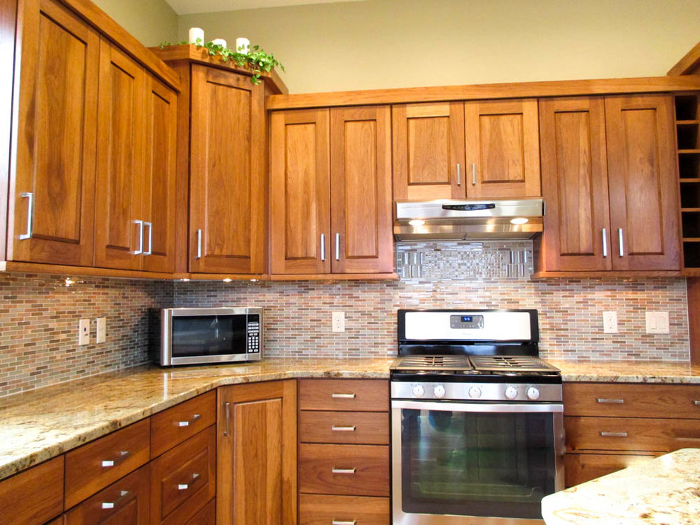 Exempel på ett mellanstort klassiskt kök, med en undermonterad diskho, luckor med upphöjd panel, skåp i mellenmörkt trä, granitbänkskiva, rostfria vitvaror, en köksö, flerfärgad stänkskydd, stänkskydd i stickkakel, ljust trägolv och brunt golv