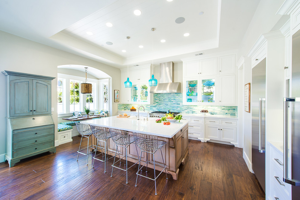 Example of a large beach style l-shaped dark wood floor and brown floor open concept kitchen design in Los Angeles with white cabinets, stainless steel appliances, an island, recessed-panel cabinets, quartz countertops, multicolored backsplash, mosaic tile backsplash, an undermount sink and white countertops