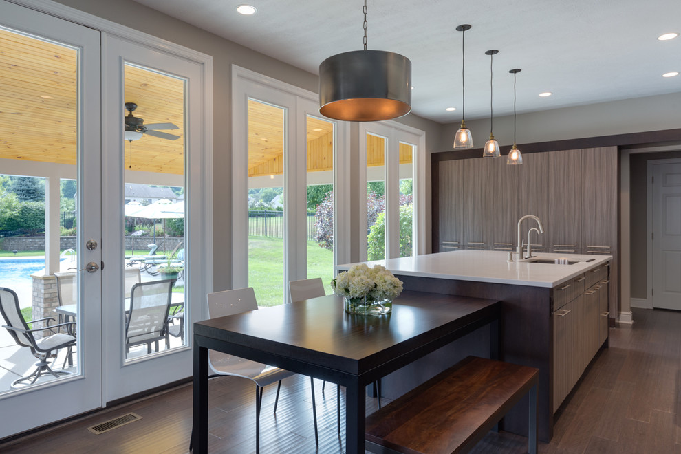 Eat-in kitchen - mid-sized transitional l-shaped dark wood floor and brown floor eat-in kitchen idea in Other with an undermount sink, flat-panel cabinets, brown cabinets, laminate countertops, gray backsplash, glass sheet backsplash, paneled appliances and an island