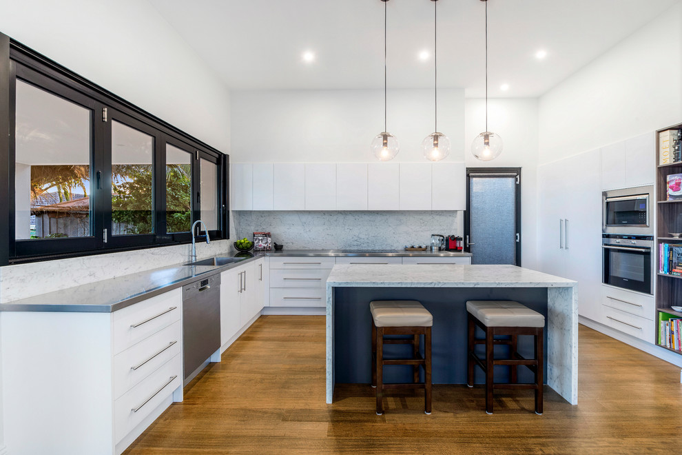 Foto di una cucina design di medie dimensioni con paraspruzzi grigio, elettrodomestici in acciaio inossidabile, pavimento in legno massello medio, lavello sottopiano, ante bianche e top in marmo