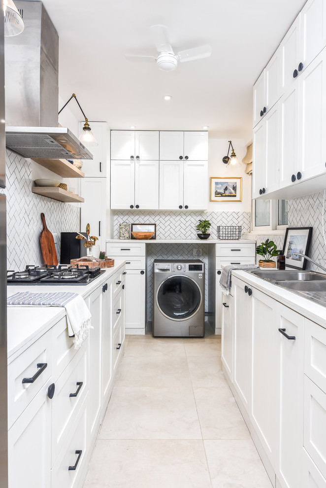 Trendy u-shaped beige floor enclosed kitchen photo in Bengaluru with a double-bowl sink, shaker cabinets, white cabinets, white backsplash, stainless steel appliances, no island and white countertops