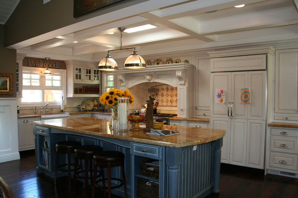 Open concept kitchen - mid-sized country l-shaped dark wood floor and brown floor open concept kitchen idea in Santa Barbara with a farmhouse sink, raised-panel cabinets, white cabinets, granite countertops, beige backsplash, ceramic backsplash, stainless steel appliances and an island