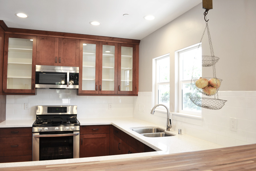 This is an example of a medium sized classic u-shaped kitchen/diner in San Luis Obispo with a submerged sink, shaker cabinets, dark wood cabinets, engineered stone countertops, white splashback, metro tiled splashback, stainless steel appliances, laminate floors, no island and brown floors.