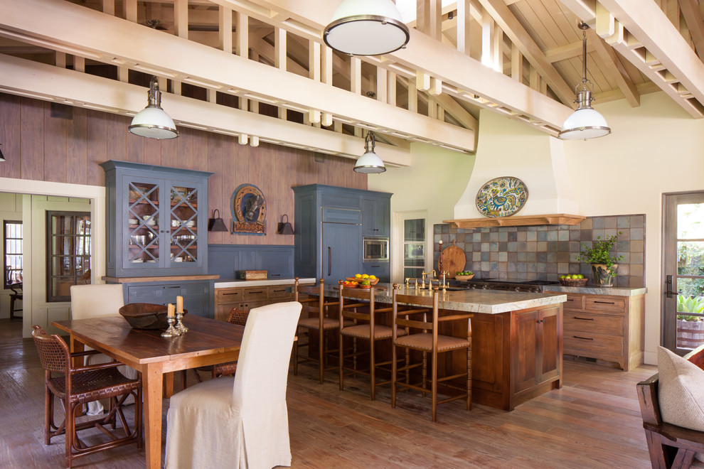 Landhaus Wohnküche mit Unterbauwaschbecken, Glasfronten, blauen Schränken, bunter Rückwand, Elektrogeräten mit Frontblende, dunklem Holzboden, Kücheninsel und braunem Boden in San Diego
