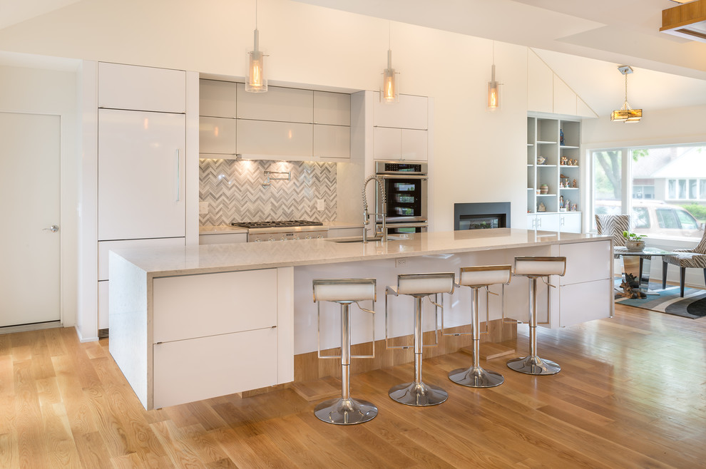 Moderne Küche mit Unterbauwaschbecken, flächenbündigen Schrankfronten, weißen Schränken, bunter Rückwand, Küchengeräten aus Edelstahl, hellem Holzboden und Kücheninsel in Boston