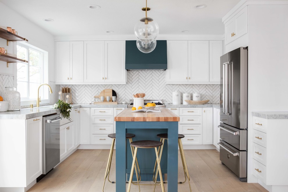 Modelo de cocinas en U tradicional renovado, de tamaño medio, abierto, con fregadero sobremueble, puertas de armario blancas, encimera de mármol, salpicadero blanco, salpicadero de azulejos de cerámica, suelo de madera clara, una isla, armarios estilo shaker, electrodomésticos de acero inoxidable y suelo beige