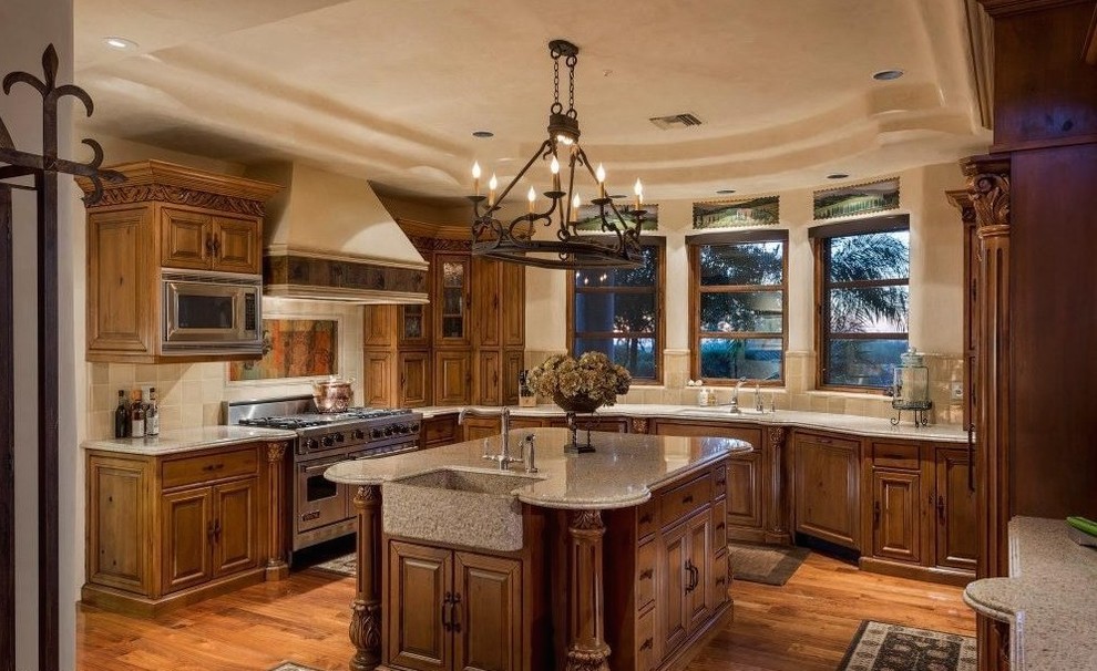 Inspiration for a huge mediterranean u-shaped light wood floor and brown floor open concept kitchen remodel in Dallas with a drop-in sink, glass-front cabinets, dark wood cabinets, granite countertops, white backsplash, ceramic backsplash, black appliances, an island and multicolored countertops
