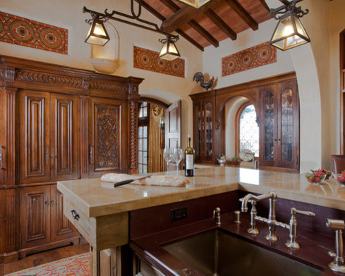 Example of a huge tuscan u-shaped dark wood floor and brown floor eat-in kitchen design in San Francisco with an island, a farmhouse sink, raised-panel cabinets, dark wood cabinets, soapstone countertops, red backsplash, brick backsplash and black appliances