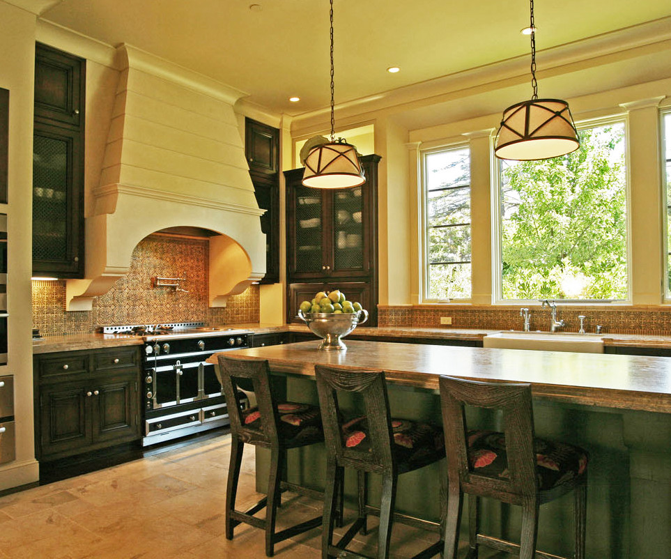 Foto på ett stort medelhavsstil kök, med en rustik diskho, luckor med infälld panel, skåp i slitet trä, granitbänkskiva, flerfärgad stänkskydd, stänkskydd i keramik, rostfria vitvaror, mörkt trägolv och en köksö