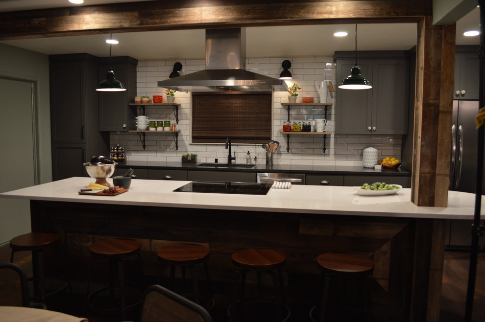 Example of a large mountain style single-wall dark wood floor open concept kitchen design in Sacramento with an undermount sink, shaker cabinets, gray cabinets, quartz countertops, white backsplash, ceramic backsplash, stainless steel appliances and an island
