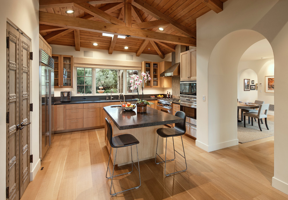 Mediterranean u-shaped open plan kitchen in Santa Barbara with a submerged sink, shaker cabinets, light wood cabinets, black splashback and stainless steel appliances.