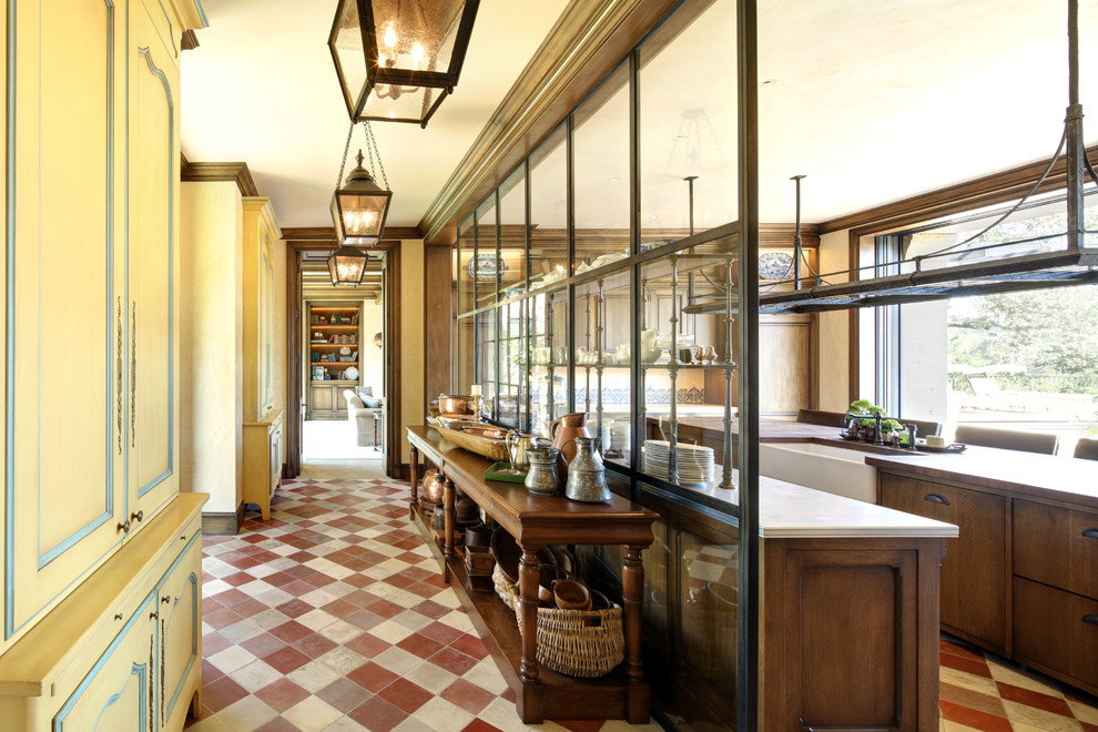 Immagine di una cucina parallela mediterranea con lavello stile country, ante in legno bruno e pavimento multicolore