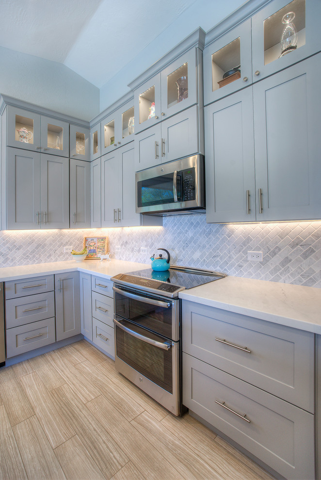Exempel på ett mellanstort modernt kök, med en undermonterad diskho, skåp i shakerstil, vita skåp, marmorbänkskiva, grått stänkskydd, stänkskydd i tunnelbanekakel, rostfria vitvaror, ljust trägolv, en köksö och brunt golv
