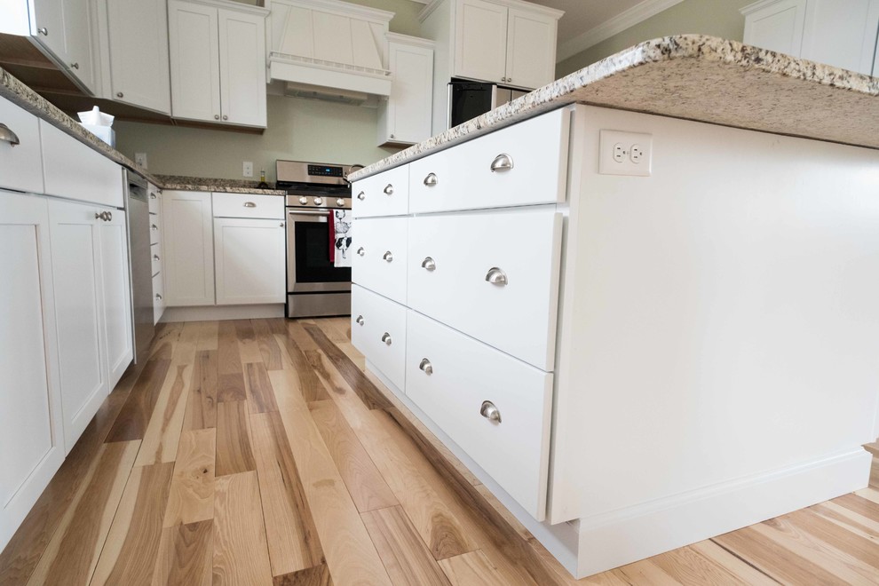 Inredning av ett lantligt kök och matrum, med en dubbel diskho, vita skåp, granitbänkskiva, rostfria vitvaror, ljust trägolv och en köksö