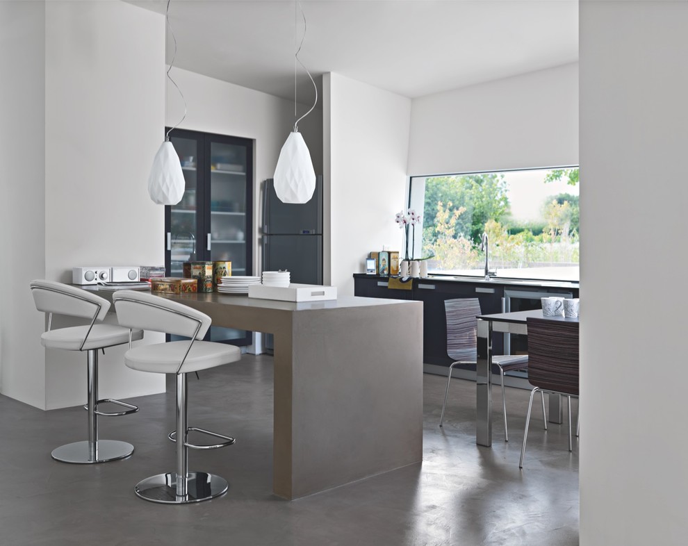 Immagine di una cucina minimal di medie dimensioni con ante di vetro, ante nere, top in cemento, elettrodomestici in acciaio inossidabile e pavimento in cemento