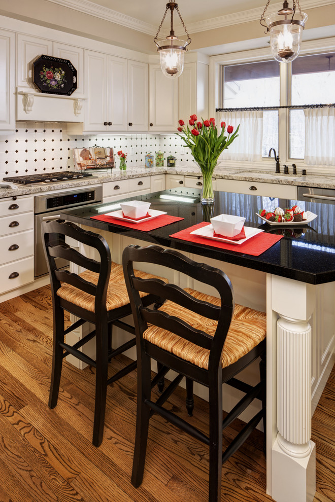 Klassisk inredning av ett kök, med luckor med upphöjd panel, vita skåp, vitt stänkskydd och rostfria vitvaror