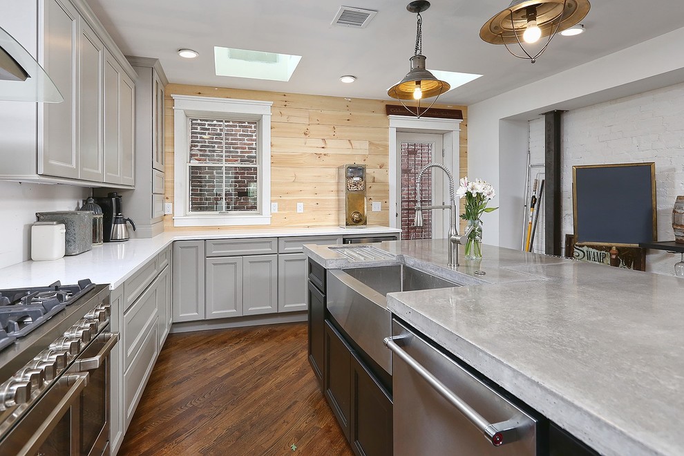 Mid-sized urban l-shaped medium tone wood floor enclosed kitchen photo in Philadelphia with a farmhouse sink, recessed-panel cabinets, gray cabinets, concrete countertops, stainless steel appliances and an island