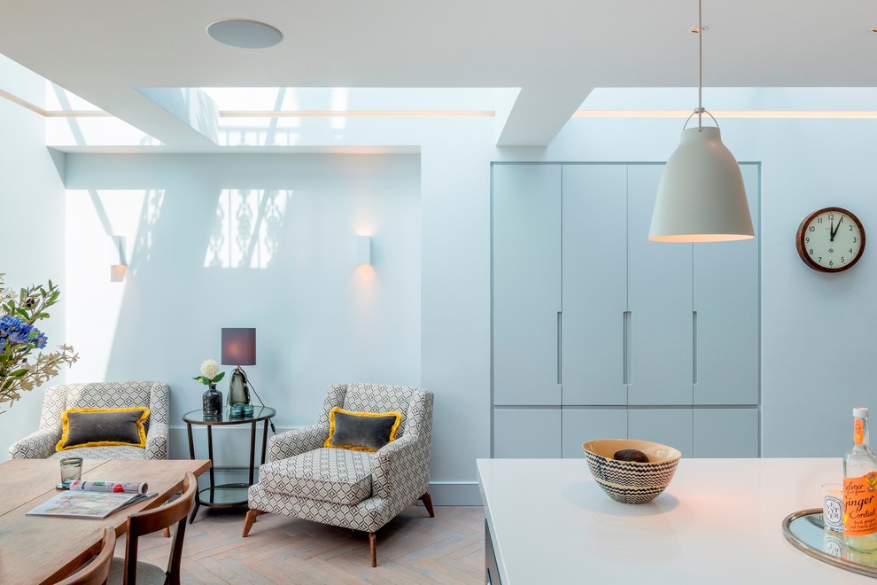 Moderne Wohnküche mit flächenbündigen Schrankfronten, grauen Schränken, hellem Holzboden und Kücheninsel in London
