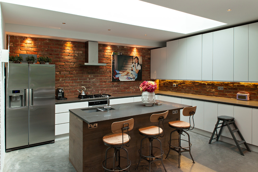 Moderne Küche in L-Form mit Doppelwaschbecken, flächenbündigen Schrankfronten, weißen Schränken, Küchengeräten aus Edelstahl, Betonboden und Kücheninsel in London