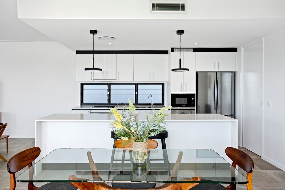 Inspiration for a medium sized contemporary single-wall open plan kitchen in Gold Coast - Tweed with a single-bowl sink, flat-panel cabinets, white cabinets, engineered stone countertops, stainless steel appliances, cement flooring, an island, grey floors and white worktops.