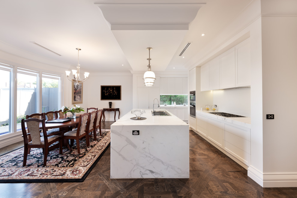 Design ideas for a large classic l-shaped kitchen/diner in Melbourne with a double-bowl sink, flat-panel cabinets, white cabinets, white splashback, an island, brown floors and white worktops.