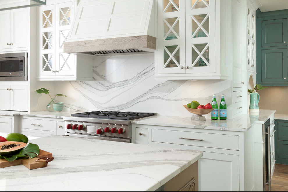 Bild på ett stort, avskilt vintage vit vitt kök, med en undermonterad diskho, luckor med infälld panel, bänkskiva i kvarts, vitt stänkskydd, rostfria vitvaror, mörkt trägolv, en köksö, brunt golv, vita skåp och stänkskydd i sten