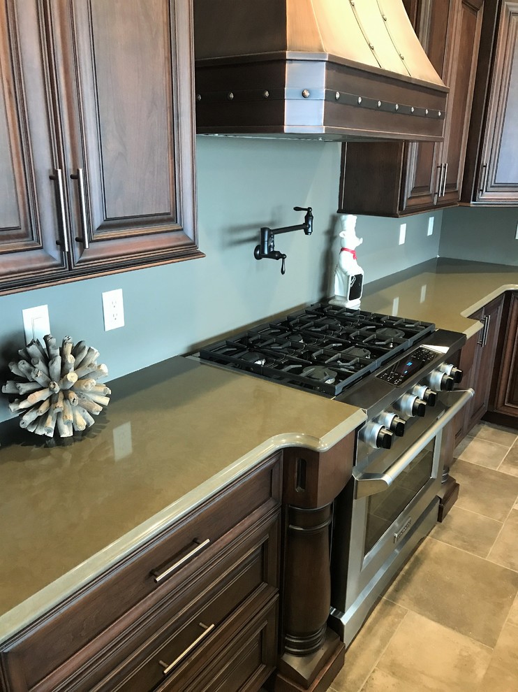 This is an example of a large classic galley kitchen/diner in Other with a submerged sink, raised-panel cabinets, dark wood cabinets, engineered stone countertops, stainless steel appliances, ceramic flooring, an island and grey floors.