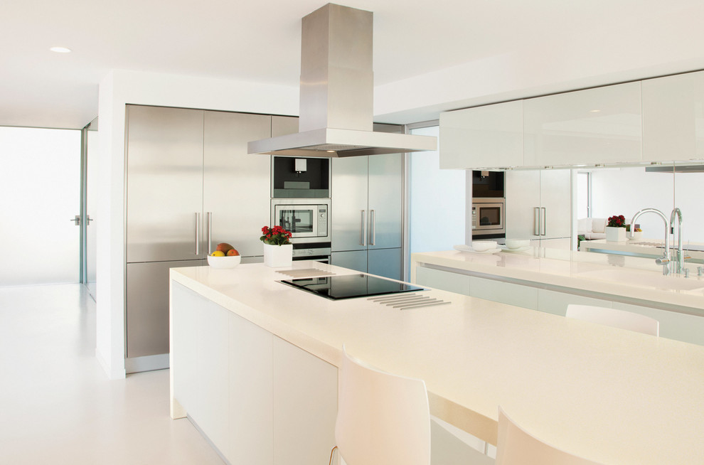 Esempio di un cucina con isola centrale minimal con ante lisce, ante in acciaio inossidabile, paraspruzzi a specchio e elettrodomestici in acciaio inossidabile