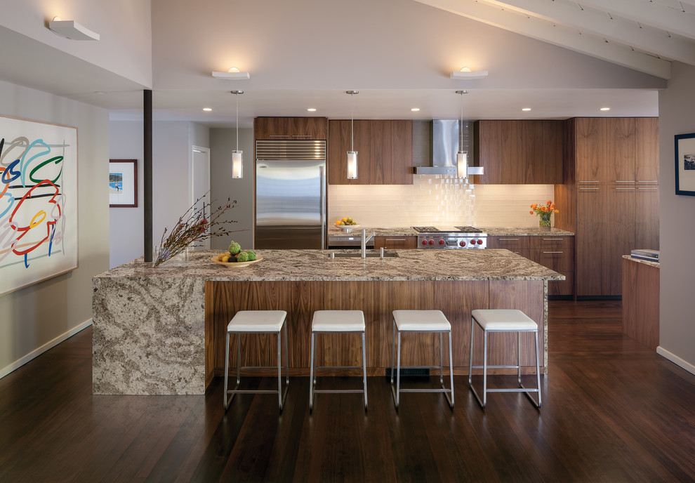 Moderne Küche mit Unterbauwaschbecken, flächenbündigen Schrankfronten, dunklen Holzschränken, Küchenrückwand in Weiß, Rückwand aus Metrofliesen, Küchengeräten aus Edelstahl, dunklem Holzboden und Kücheninsel in Minneapolis