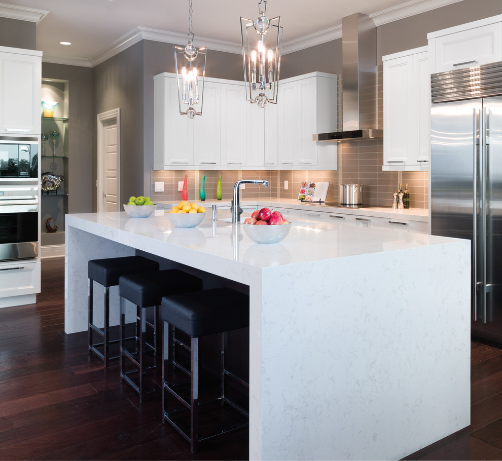 This is an example of a traditional kitchen in Minneapolis with recessed-panel cabinets, white cabinets, grey splashback, metro tiled splashback, stainless steel appliances, dark hardwood flooring and an island.