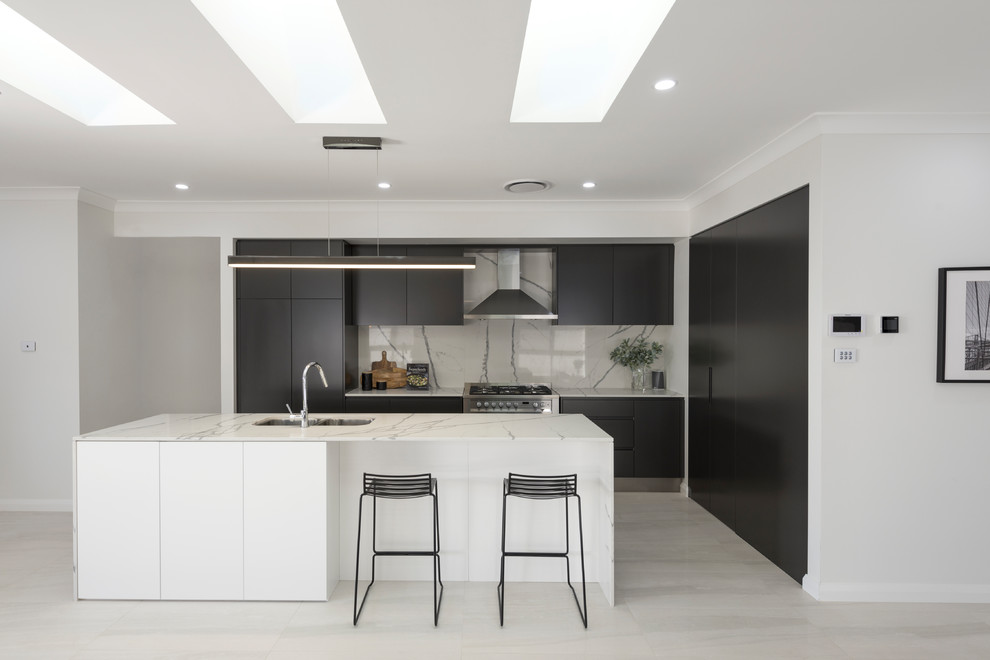 Inspiration for a contemporary l-shaped kitchen in Sydney with a submerged sink, flat-panel cabinets, black cabinets, grey splashback, integrated appliances, an island, beige floors and grey worktops.