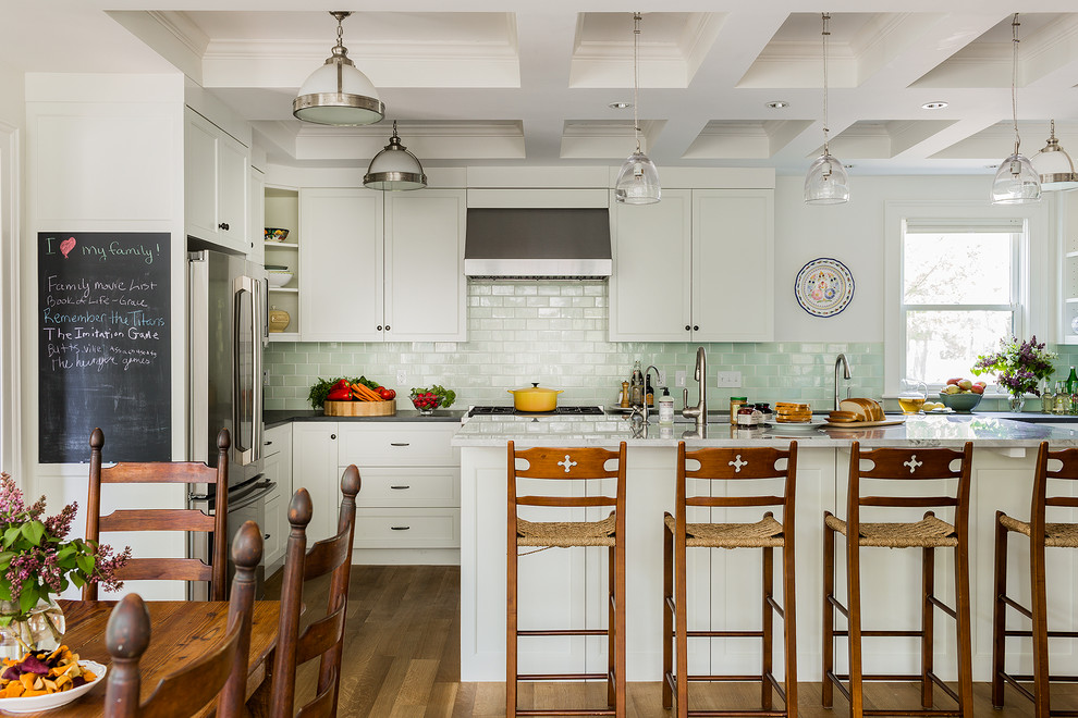 Farmhouse l-shaped medium tone wood floor eat-in kitchen photo in Boston with shaker cabinets, an island, white cabinets, green backsplash, subway tile backsplash and stainless steel appliances