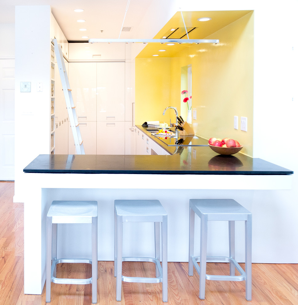 Modelo de cocina minimalista con fregadero bajoencimera, armarios con paneles lisos, puertas de armario blancas, encimera de esteatita, salpicadero amarillo y electrodomésticos blancos