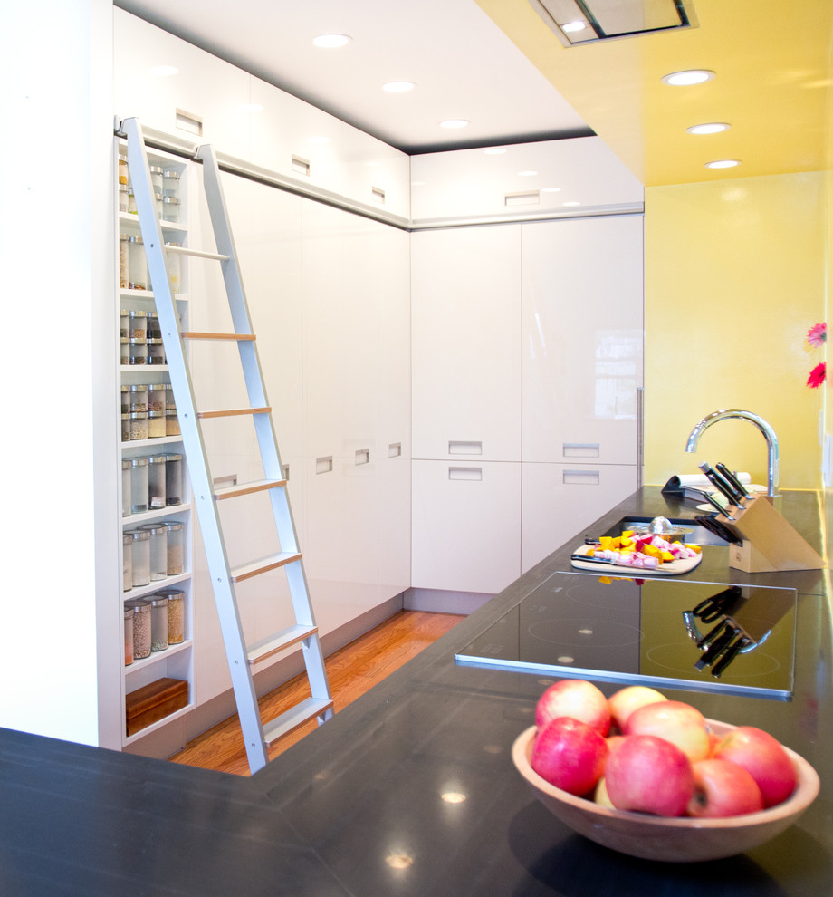Пример оригинального дизайна: п-образная кухня в стиле модернизм с обеденным столом, врезной мойкой, плоскими фасадами, белыми фасадами, столешницей из талькохлорита, желтым фартуком и белой техникой