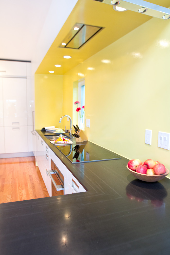 Foto di una cucina minimalista con lavello sottopiano, ante lisce, ante bianche, top in saponaria, paraspruzzi giallo e elettrodomestici bianchi