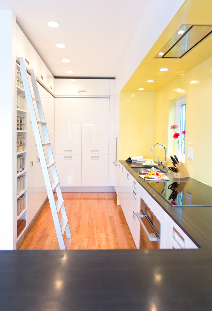 Modelo de cocina moderna con fregadero bajoencimera, armarios con paneles lisos, puertas de armario blancas, encimera de esteatita, salpicadero amarillo y electrodomésticos blancos