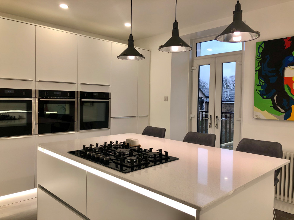 Idéer för att renovera ett stort funkis vit vitt kök och matrum, med en integrerad diskho, släta luckor, vita skåp, granitbänkskiva, vitt stänkskydd, rostfria vitvaror, vinylgolv, en köksö och grått golv