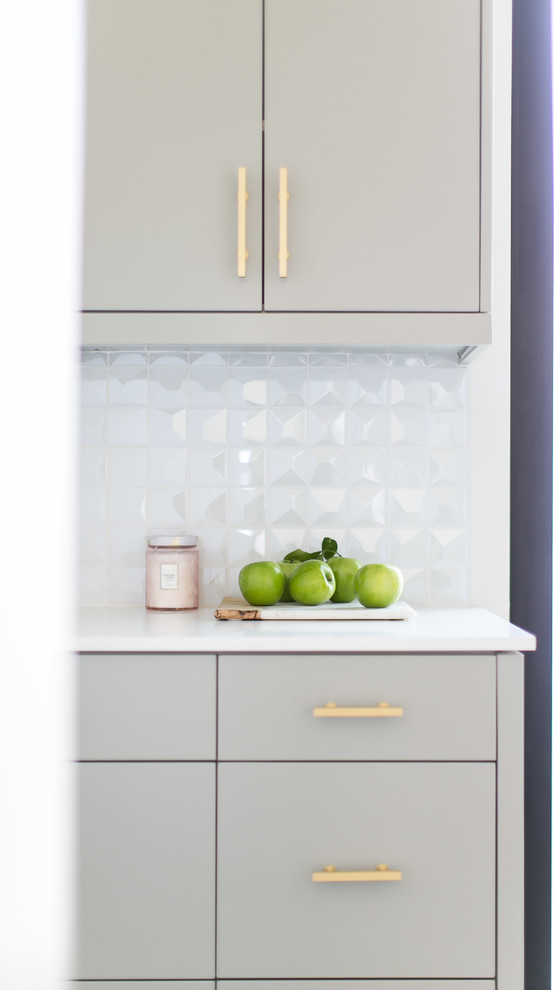 Large l-shaped kitchen pantry in Orange County with a built-in sink, flat-panel cabinets, grey cabinets, marble worktops, white splashback, glass tiled splashback, stainless steel appliances, limestone flooring and an island.