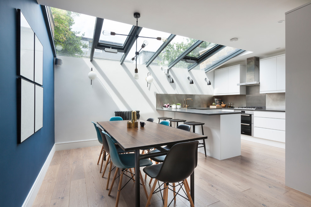Mittelgroße Moderne Küche in U-Form mit flächenbündigen Schrankfronten, weißen Schränken, Küchenrückwand in Metallic, hellem Holzboden und Halbinsel in London