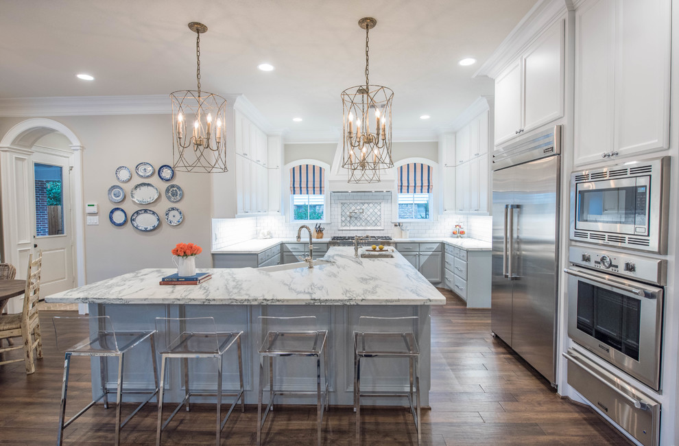Inspiration for a classic kitchen in Dallas with recessed-panel cabinets, white cabinets, white splashback, metro tiled splashback, stainless steel appliances, dark hardwood flooring and an island.