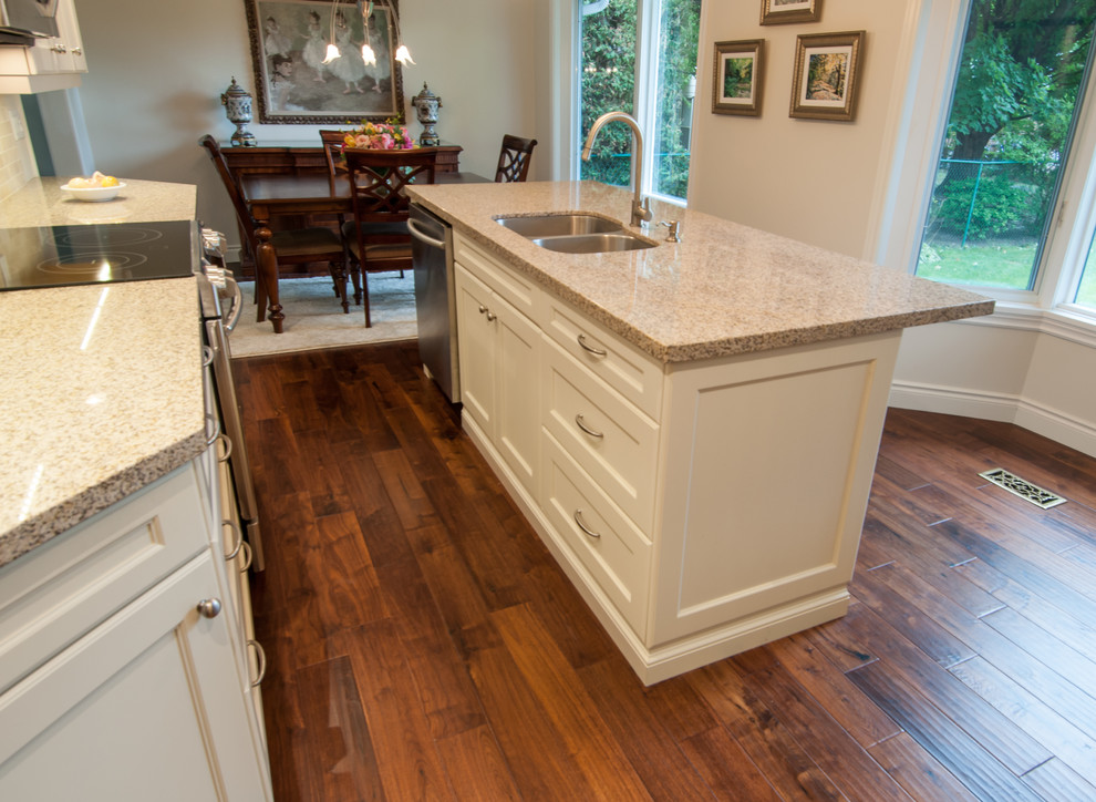 Mid-sized transitional l-shaped dark wood floor eat-in kitchen photo in Toronto with a double-bowl sink, shaker cabinets, white cabinets, granite countertops, beige backsplash, ceramic backsplash, stainless steel appliances and an island