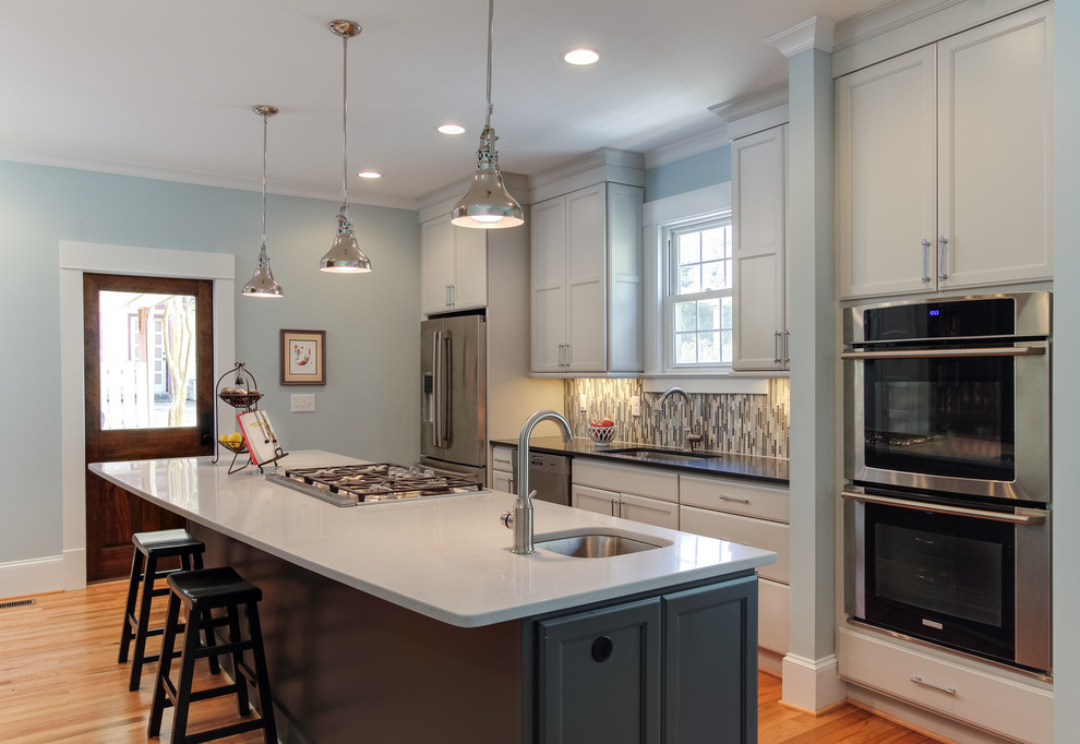 This is an example of a traditional kitchen in Raleigh with a single-bowl sink, glass tiled splashback, stainless steel appliances and an island.