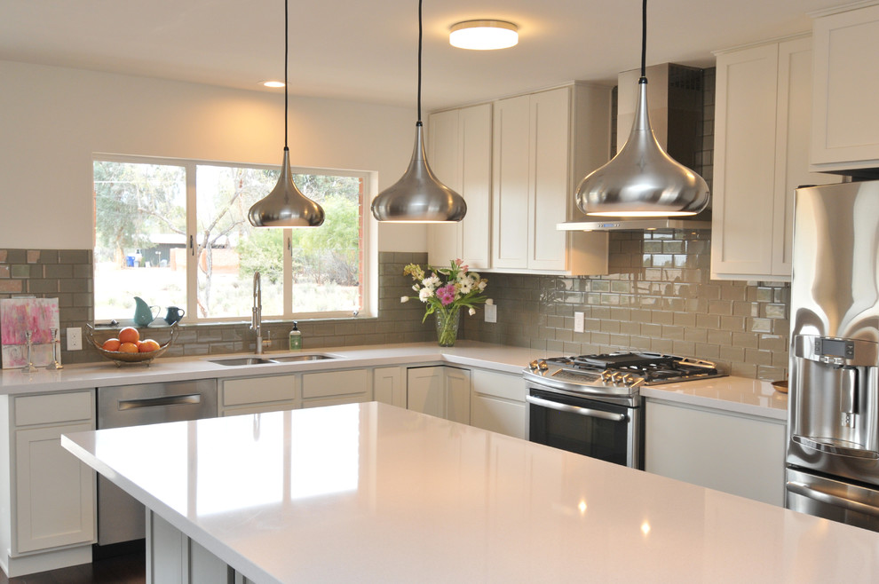 Inredning av ett modernt mellanstort kök, med en dubbel diskho, luckor med infälld panel, vita skåp, bänkskiva i kvarts, grått stänkskydd, stänkskydd i glaskakel, rostfria vitvaror och en köksö